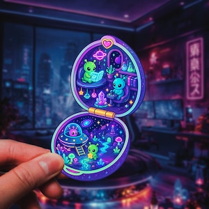 May include: A colorful sticker featuring a whimsical alien scene inside a clamshell-shaped design. The sticker depicts two aliens reading and playing games, with a spaceship and a starry night background. The color palette includes shades of purple, blue, and green.