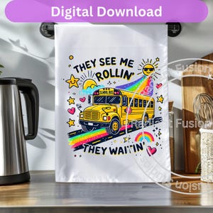 May include: A white tea towel with a yellow school bus illustration and the text "They see me rollin' They waitin'" in colorful letters. The bus is driving on a rainbow road with stars and hearts.