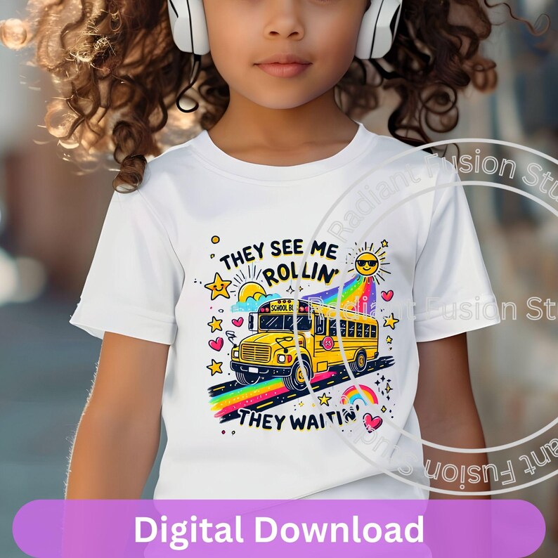 May include: A white t-shirt with a yellow school bus graphic and the text "They See Me Rollin' They Waitin'" in colorful letters. The bus is driving on a rainbow road with hearts and stars.