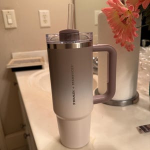 Puede incluir: Un vaso Stanley + Starbucks con asa y pajita transparente. El vaso tiene un dise&ntilde;o de dos tonos, que pasa de blanco a un gris-p&uacute;rpura apagado. El asa y la tapa son de un p&uacute;rpura apagado a juego.