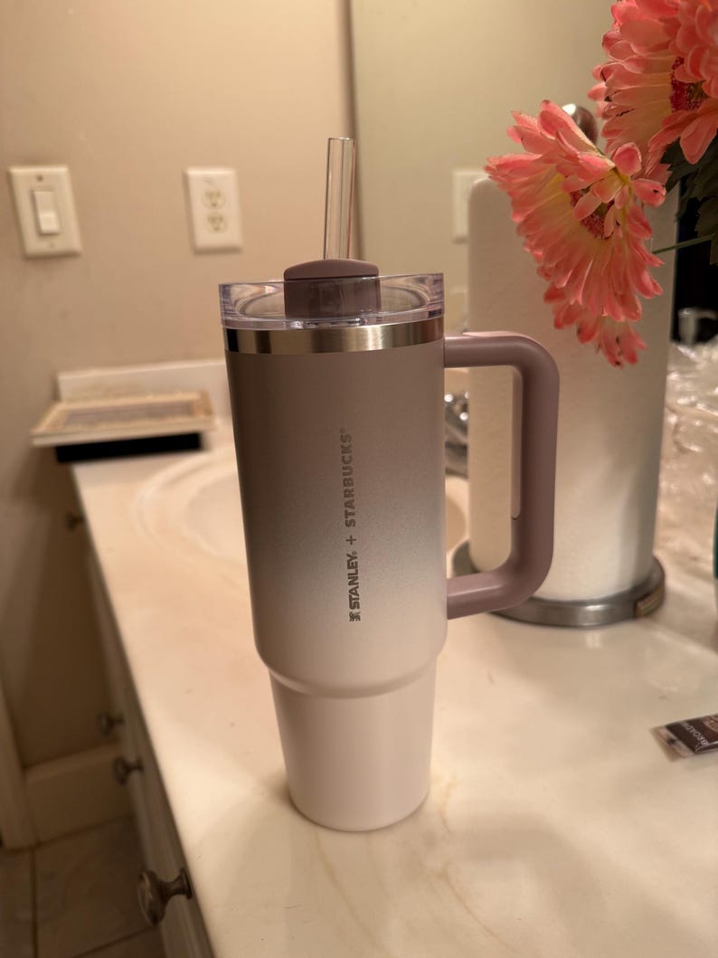 Puede incluir: Un vaso Stanley + Starbucks con asa y pajita transparente. El vaso tiene un dise&ntilde;o de dos tonos, que pasa de blanco a un gris-p&uacute;rpura apagado. El asa y la tapa son de un p&uacute;rpura apagado a juego.