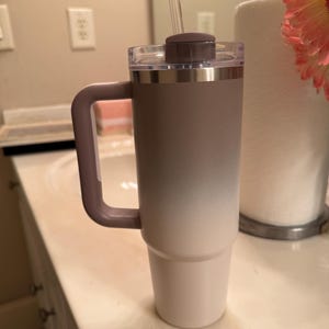 Puede incluir: Un vaso grande y aislado con asa, con un degradado de color de topo a blanco. Tiene una tapa transparente, una tapa marr&oacute;n y una pajita transparente. El asa y la tapa son de color topo. Ideal para bebidas fr&iacute;as.