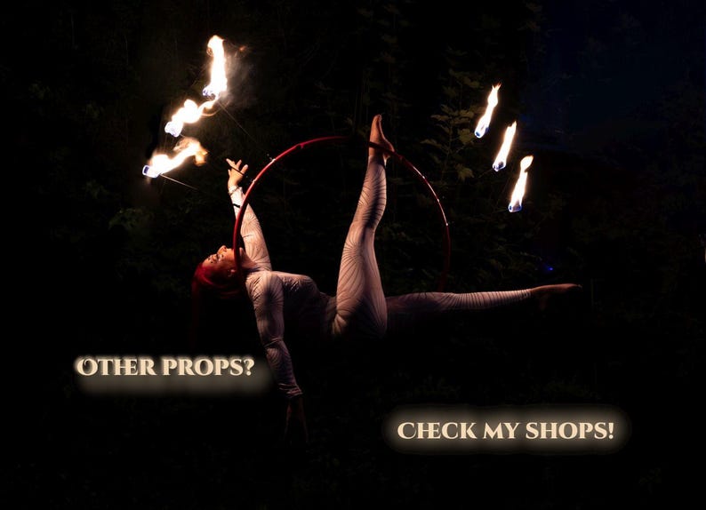 Op de afbeelding: Een artiest in een wit bodysuit voert een luchtacrobatiek uit met een rode hoepel, omringd door vlammen. De tekst "OTHER PROPS? CHECK MY SHOPS!" is zichtbaar in de afbeelding.