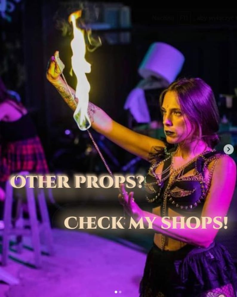 Op de afbeelding: Een persoon houdt een rekwisiet met een vlam vast. De afbeelding bevat de tekst "OTHER PROPS? CHECK MY SHOPS!". De persoon draagt een zwarte outfit met gouden kettingaccenten. De achtergrond is donker met paarse en roze verlichting.