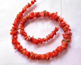 May include: A strand of red coral beads, with each bead having an irregular, chipped shape. The beads are strung on a thin wire.