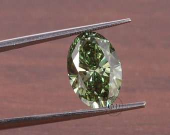 May include: A green oval-shaped gemstone held by tweezers. The gemstone has a brilliant cut and facets.