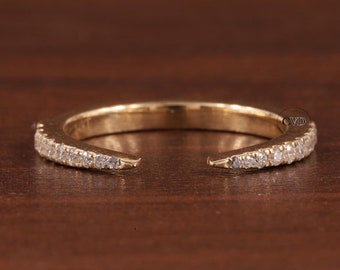 May include: A gold band ring with a row of small diamonds set into the band. The ring is open on one side, making it a half eternity band.