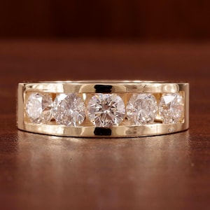May include: A gold band with six round diamonds set in a channel setting.