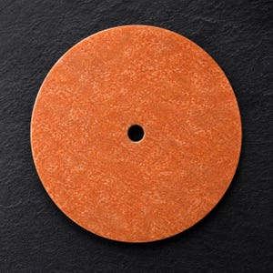 Puede incluir: Un disco circular y plano de color naranja con una superficie moteada y texturizada, que presenta un único orificio circular en el centro. El objeto muestra un tono naranja vibrante y constante en toda su superficie, con aspecto granulado.