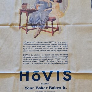 Puede incluir: Saco de harina Hovis vintage de color crema con una ilustración impresa de una mujer y un niño. El texto "HER FAVOURITE" está en la parte superior, con el logotipo y el texto de Hovis en la parte inferior. El saco está hecho en el Reino Unido.