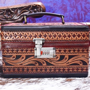 May include: A brown leather jewelry box with intricate tooled designs and a silver combination lock.
