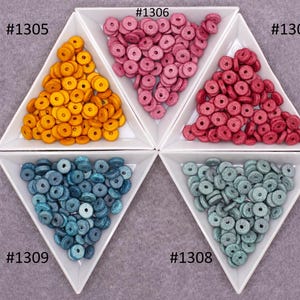 Op de afbeelding: Vier driehoekige schalen gevuld met houten kralen in vier verschillende kleuren: geel, roze, blauw en teal. Elke schaal is gelabeld met een nummer: #1305, #1306, #1307 en #1308.