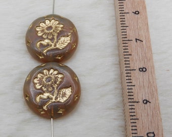 Könnte beinhalten: Zwei runde braune Glasperlen mit goldenen Blumenmustern. Die Perlen sind auf einem Draht aufgefädelt und haben einen Durchmesser von etwa 2,5 cm.