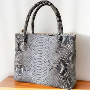 May include: A gray and black snakeskin tote bag with two top handles.