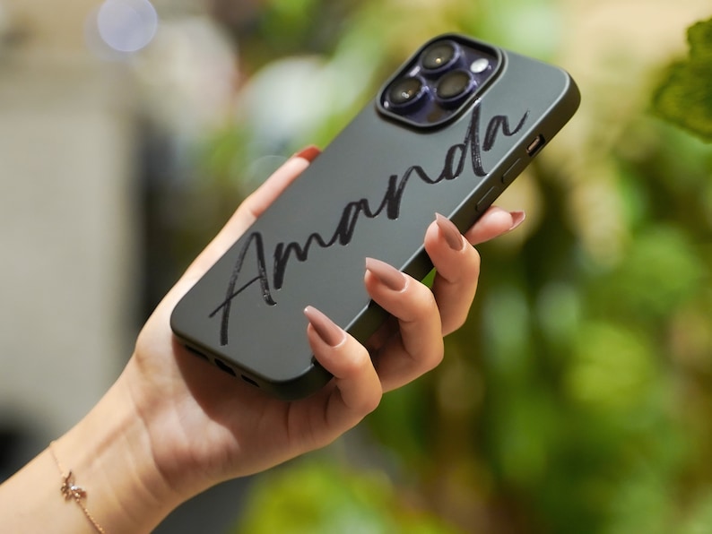 May include: A black phone case with the name "Amanda" written in white cursive script.