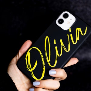 May include: Black phone case with a yellow "Olivia" name written in a brushstroke font.