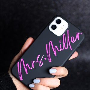 May include: Black phone case with a pink inscription that reads "Mrs. Miller".
