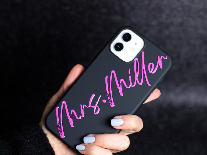 May include: Black phone case with a pink inscription that reads "Mrs. Miller".