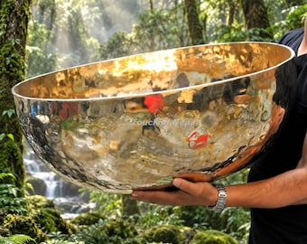 May include: A large, polished, hammered brass singing bowl with a reflective, golden surface. The bowl features the text "Touch of Nepal" etched onto its side. The metal has a distinct, uneven texture from the hand-hammering process.
