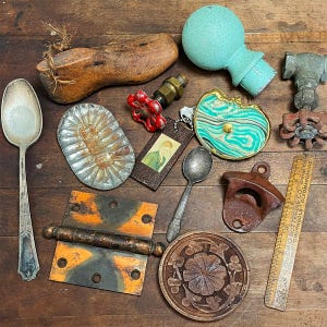 May include: A collection of vintage objects including a wooden shoe form, a teal finial, a metal valve, a silver spoon, a fluted tin mold, a small portrait tag, a green and white marbled disc, a rusty bottle opener, a hinge, and a wooden ruler.