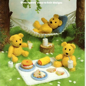 May include: A book cover with the title "Jean Greenhowe's Toy Collection", showcasing knitted teddy bears in a picnic scene. The bears are yellow and surrounded by miniature food items. The background is green, with a hammock and the text "Over twenty easy-to-knit designs".