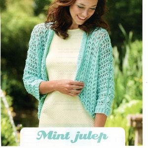 May include: A woman wearing a light blue crochet cardigan with a lacy pattern. The cardigan is open in the front and has a relaxed fit. The text "Mint Julep" is written in a stylized font below the image. The text "A Little Bit Tricky" is written in a smaller font below the title.