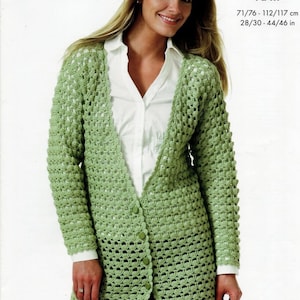Puede incluir: Un cárdigan de crochet verde con cierre de botones. El cárdigan es largo y tiene un corte holgado. Está hecho con un patrón de punto sencillo y tiene un dobladillo festoneado. El cárdigan se muestra siendo usado por una modelo. "double knit" y "71/76 - 112/117 cm 28/30 - 44/46 in" están escritos en texto negro sobre un fondo blanco.