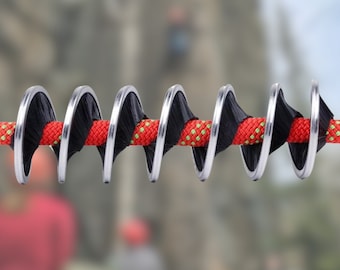 Może przedstawiać: Czerwono-czarna lina ze srebrnymi metalowymi pierścieniami, zwinięta w spiralę. Lina jest przeznaczona do wspinaczki i aktywności na świeżym powietrzu.