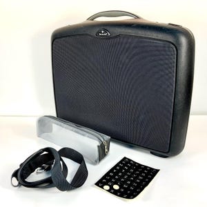 Puede incluir: Maletín Samsonite negro con asa, panel de tela negra y correa gris. Incluye un estuche transparente, una correa y una hoja de pegatinas del alfabeto. El maletín tiene el logotipo de Samsonite.