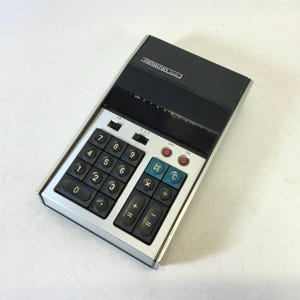 May include: A silver and black calculator with a black display and a number pad with black buttons. The calculator has the text "ZUUNDEZHA" on the top.