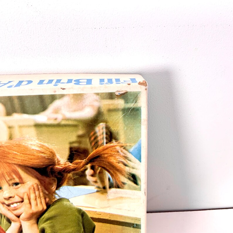 May include: A vintage book cover featuring a smiling girl with red pigtails, wearing a green shirt. The book title is visible in blue text. The cover has a slightly worn appearance.