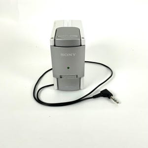 May include: A silver and white Sony audio device with a black cord and a 3.5mm jack. The device has a dial and a green light. The Sony logo is visible on the front.