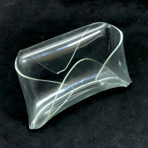 Puede incluir: Un cuenco de plástico transparente con un diseño curvo único. El cuenco está hecho de una sola pieza de plástico y tiene un acabado liso y brillante.