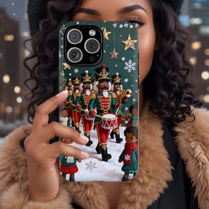 May include: A phone case featuring a festive design with a marching band of toy soldiers in red, green, and black uniforms. The case has a dark green background with snowflakes and gold stars, creating a holiday theme.