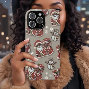 May include: A gray iPhone case with a Christmas theme featuring a black and brown Santa Claus and Mrs. Claus, a snowman, and snowflakes.