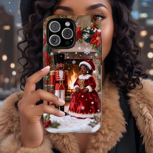 May include: A phone case featuring a Christmas scene with a nutcracker and a woman in a red dress, set against a fireplace with poinsettias and snowflakes. The case has a black camera module.