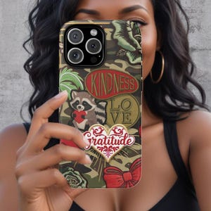 May include: A camouflage phone case with a variety of colorful patches. The patches include a raccoon, a heart with the word "gratitude", a bow, and the words "kindness" and "love".