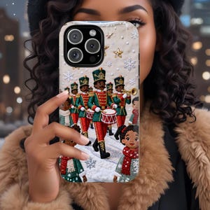 May include: A phone case featuring a marching band of toy soldiers in red and green uniforms, playing drums and trumpets. The case has a winter theme with snowflakes and stars. The case is held up in front of a person.