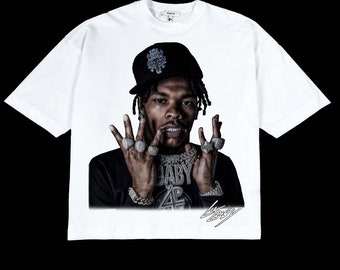 May include: White t-shirt with a black and white image of a rapper wearing a black baseball cap, a gold chain, and multiple rings. The rapper is making a hand gesture and the image includes the text "Baby" and a signature.