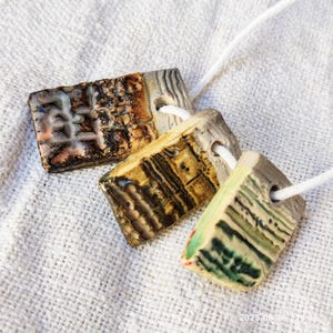 Trío de colgantes de cerámica, diversos dijes de colores y formas para la fabricación de joyas.