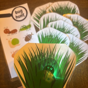May include: A green and white ladybug hiding in the grass. The ladybug has black spots and a green iridescent sheen. The image is part of a game called "bug hunt".