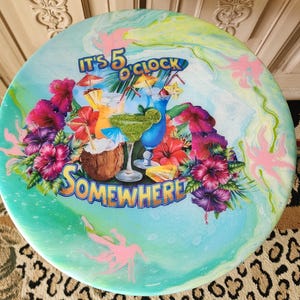 May include: A white ceramic mug with a black handle and the text "But First, Coffee" in a handwritten style. The mug is on a white surface. The mug is approximately 4 inches tall.