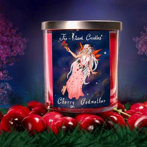 Op de afbeelding: Een rode glazen potkaars met een zilveren deksel. Het etiket toont een fee met roze vleugels en een roze jurk, die een rode kers vasthoudt. De tekst op het etiket luidt "Fairy Kissed Candles" en "Cherry Godmother".