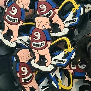 May include: A selection of shoe charms. Each charm depicts a cartoon figure in a maroon and blue jersey with the number 9 and the word "BURNLEY". The figure stands on a white shoe with "ROVERS".