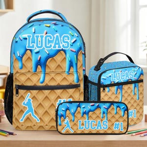 May include: A backpack, lunch bag, and pencil case set featuring a waffle cone pattern with blue icing and colorful sprinkles. Each item displays the name LUCAS in white block letters, a baseball player silhouette, and the text #1 in white.