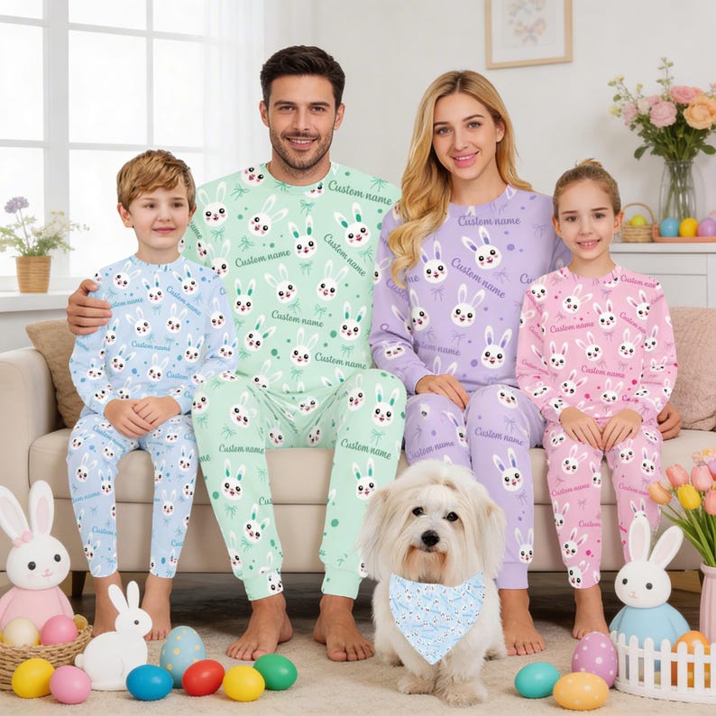 Puede incluir: Familia con pijamas de Pascua a juego. Los pijamas son de color azul claro, verde, lavanda y rosa, con un patr&oacute;n repetido de cara de conejito. El texto "Custom name" est&aacute; impreso en los pijamas. Un perro blanco con un pa&ntilde;uelo azul est&aacute; sentado frente a la familia.