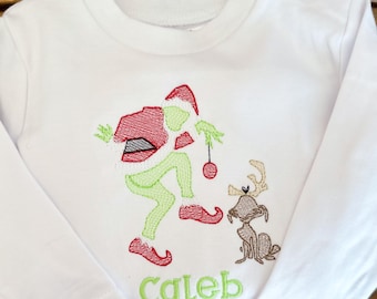 May include: White long-sleeved shirt with an embroidered image of the Grinch, a reindeer, and the name "Caleb".