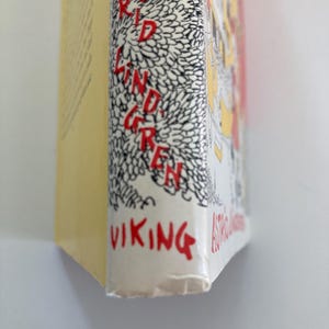 May include: A book spine with a yellow side and a white front edge featuring black line art of dense foliage. The text ASTRID LINDGREN is printed vertically in red letters, and the word VIKING is printed in red at the bottom of the white spine edge.