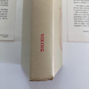May include: A beige book spine with a textured surface. The word VIKING is printed in red capital letters near the bottom. A portion of a red word is visible at the top. The book is positioned vertically against a white background.