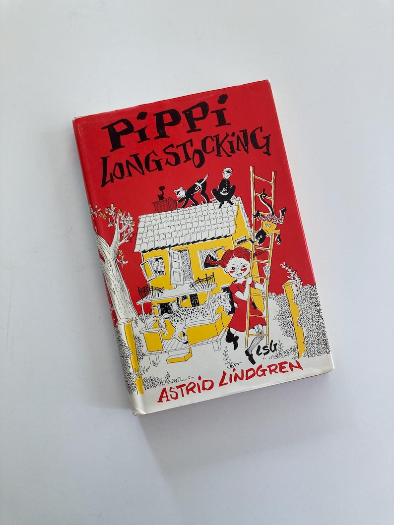 May include: A hardcover book titled Pippi Longstocking by Astrid Lindgren with a bright red cover. The illustration features a yellow house, a girl with red braids, a spotted horse, and a monkey climbing a ladder against a red background.